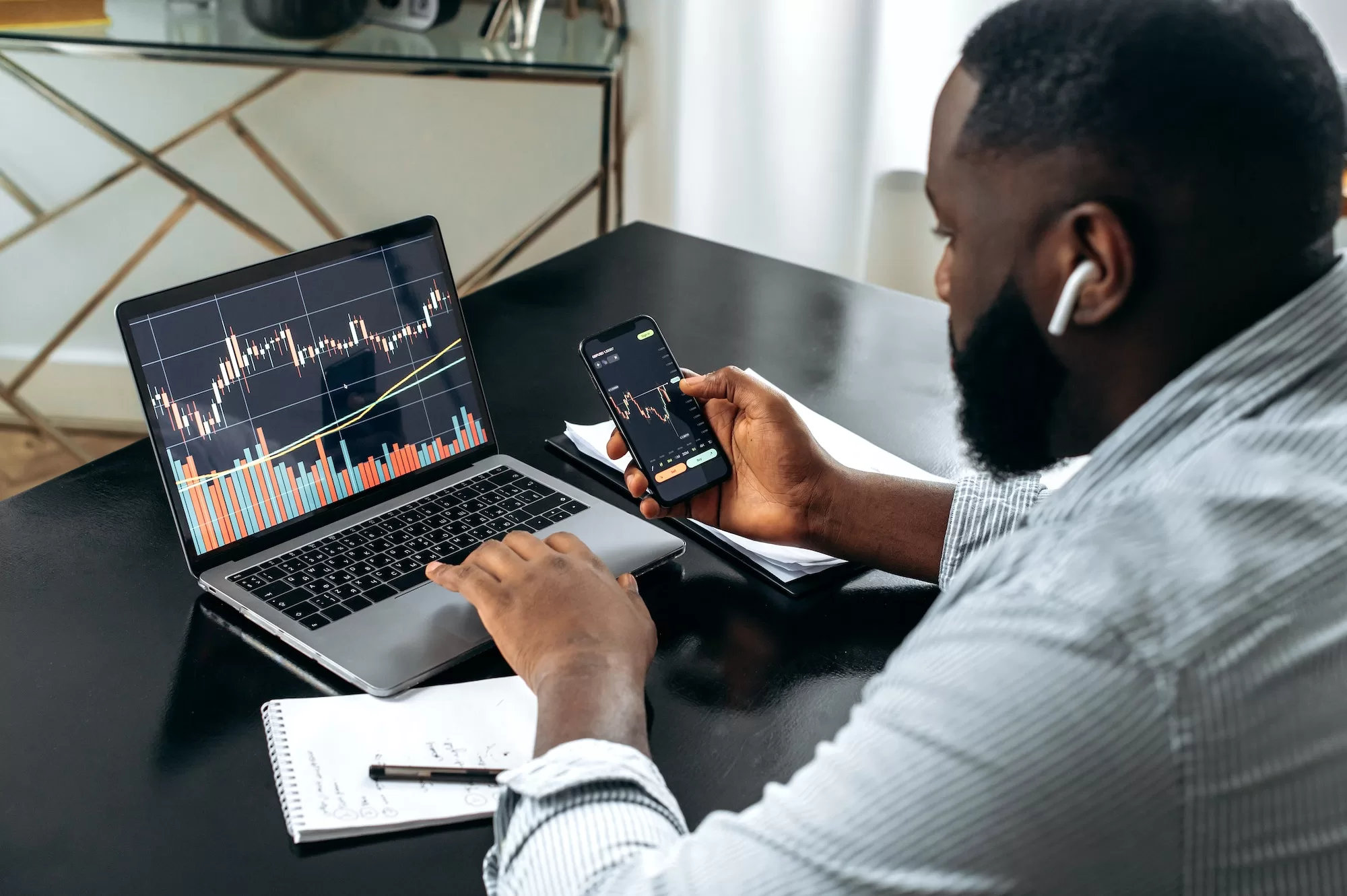 A Beginner's Guide to Trading: Important Tips to Keep in Mind Financial trading charts on laptop and smartphone screens. A successful African trader