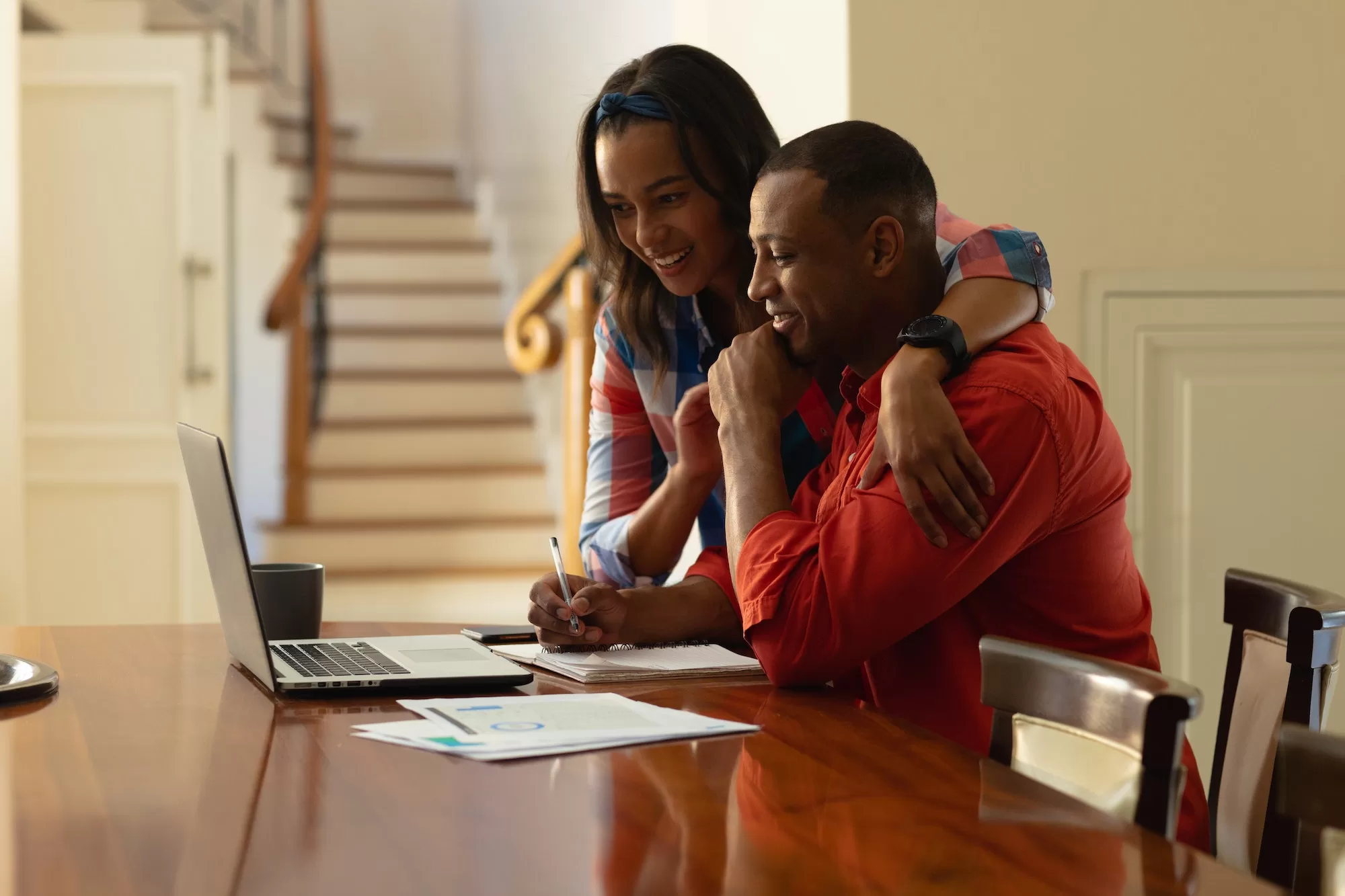 Smiling young African couple planning home budget while sitting with laptop at table | Budget When Buying a Home