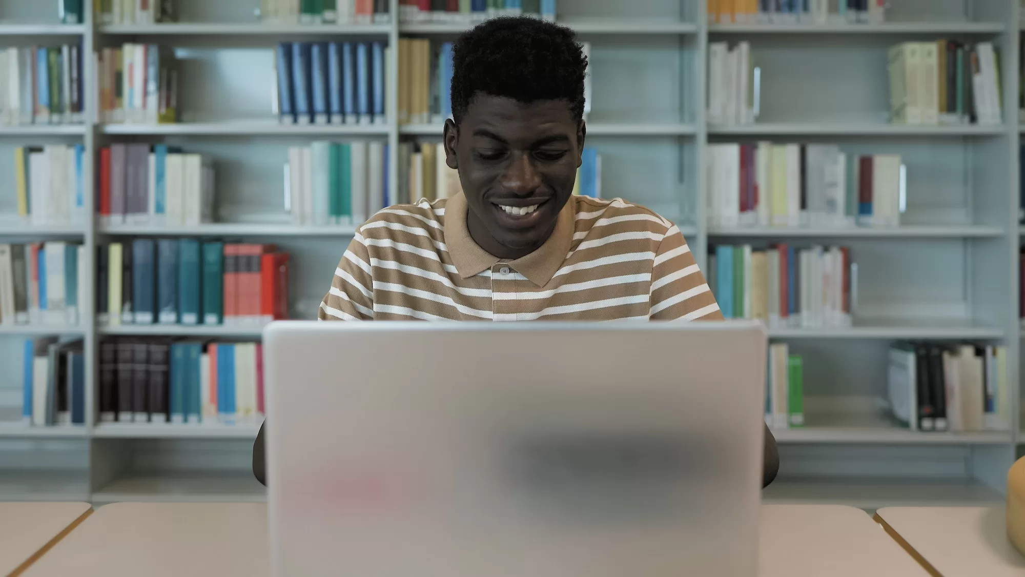 Young African student using laptop in library - Understanding the NSFAS Application Process