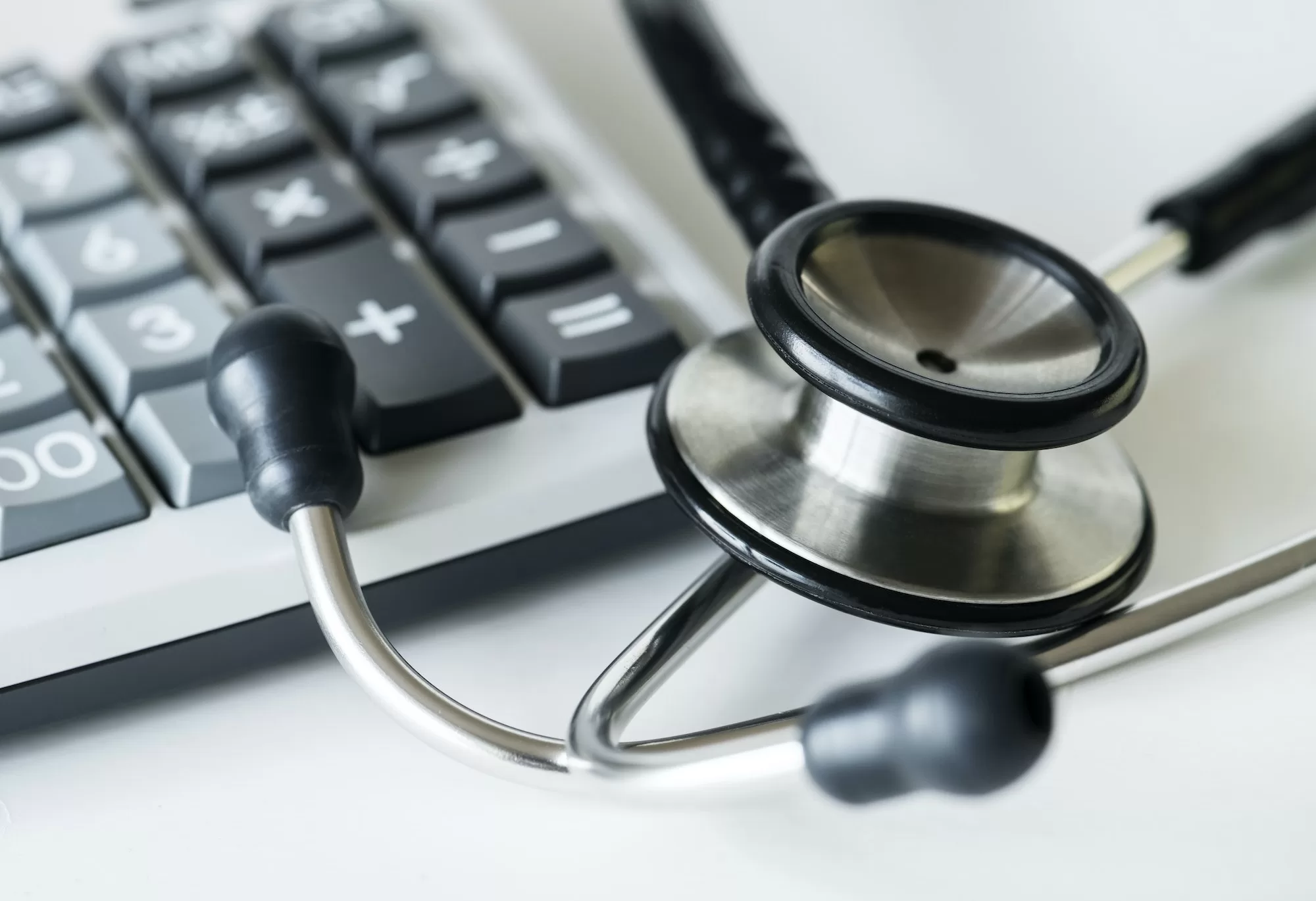 Closeup of a calculator and a stethoscope healthcare and expenses concept | A Comprehensive Guide to Claiming Medical Expenses and Disability Deductions