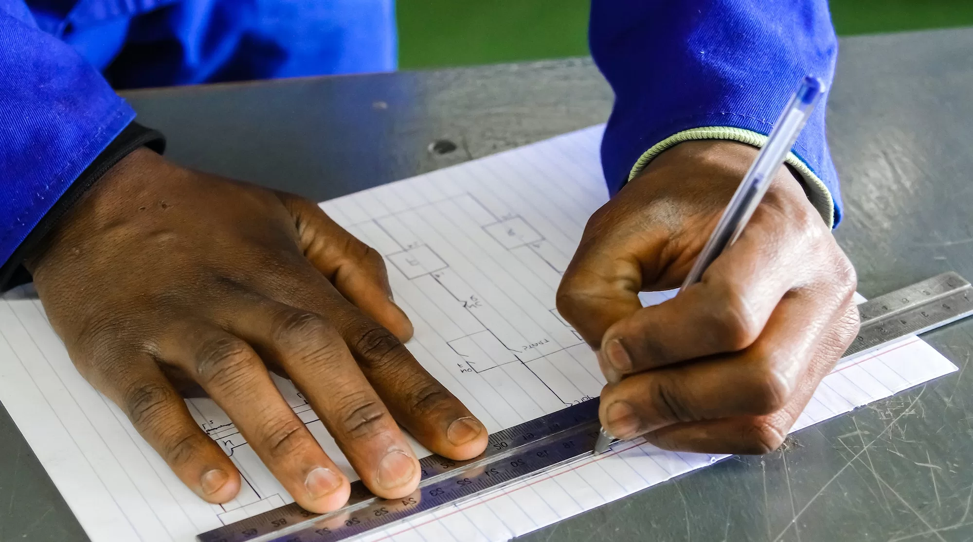 Closeup of a man using a ruler on drawing an architectural map, vocational skills | Roots Employee Vocational Training Bursary