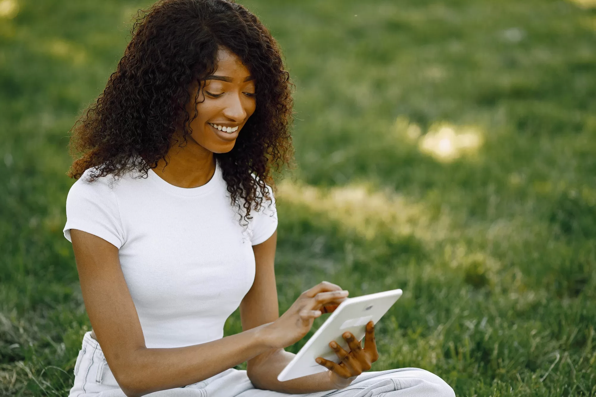 Female african student sitting on a grass and using a tablet | University of Namibia 2023 Application Guide
