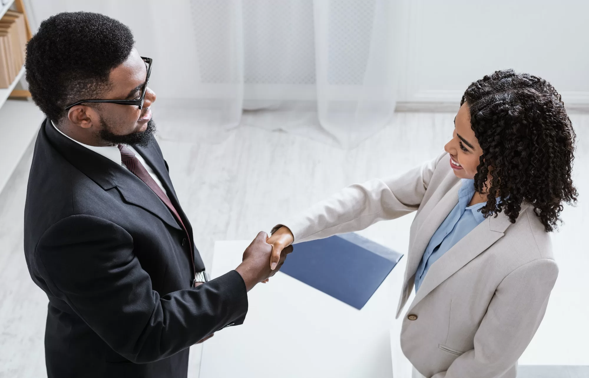 University of Namibia Career Fair and Employment Expo. Human resources manager shaking hands with successful vacancy applicant at office, above view | Why Attend the UNAM Career Fair and Employment Expo?