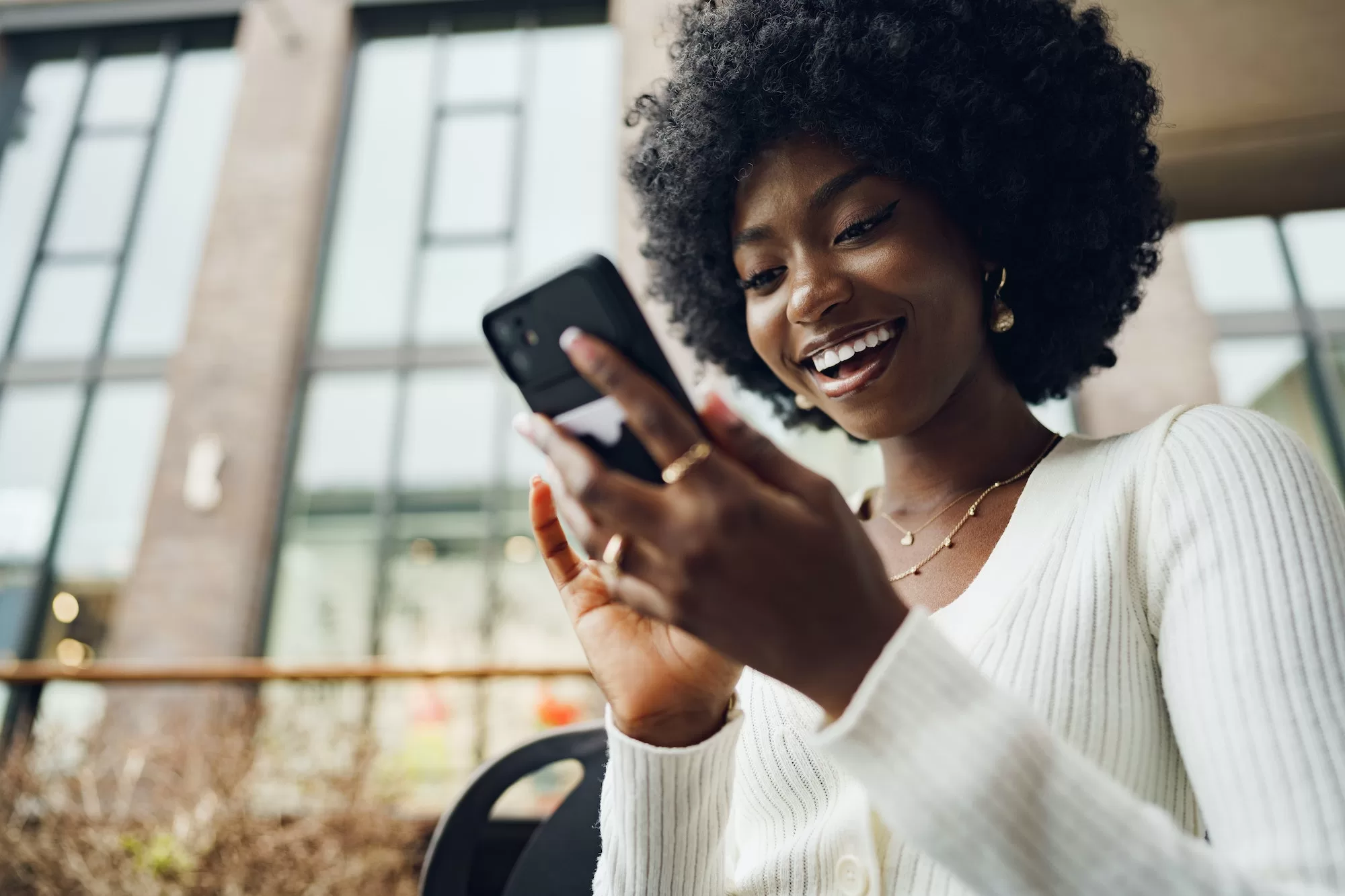 Portrait of a beautiful young african woman using her cellphone in a cafe | Protecting Customers in a Digital World with MTC Biometric SIM Registration