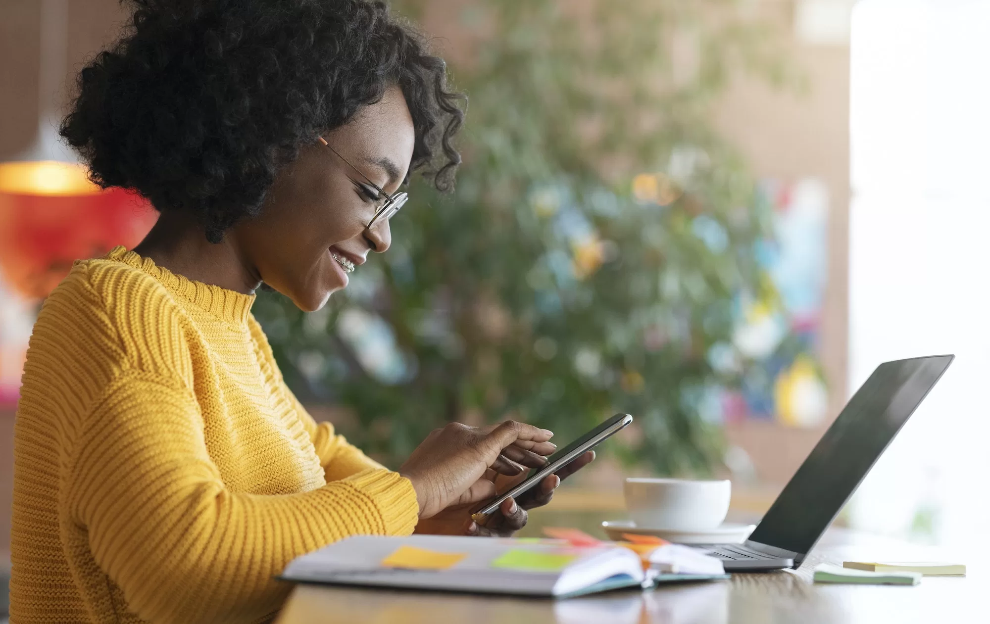 Happy afro girl freelancer using mobile phone. How to download bank statement on FNB app! Download Your Monthly Statement