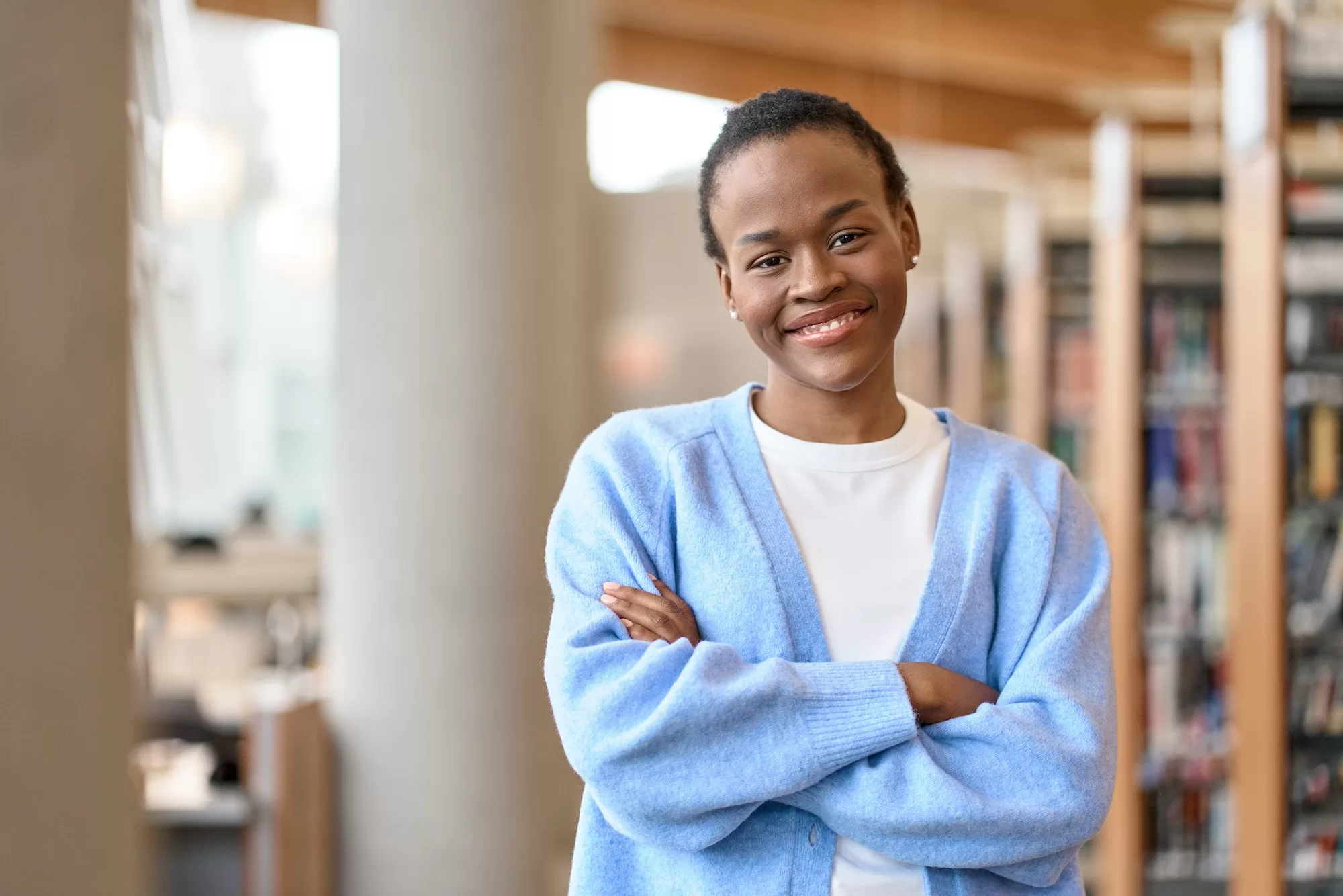 Consequences of Plagiarism: UNAM Library Guide - Happy Black African girl student standing in university library. Portrait.