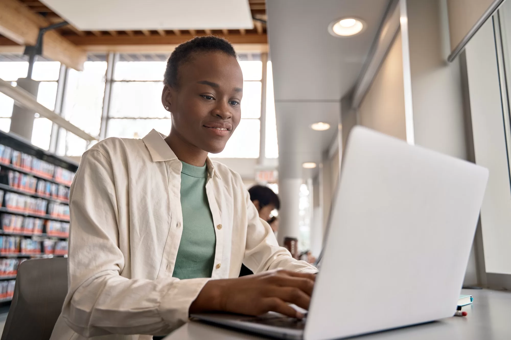 Who Qualifies for Student Internet with Inceptus. Smiling African girl student using laptop sitting in university library.