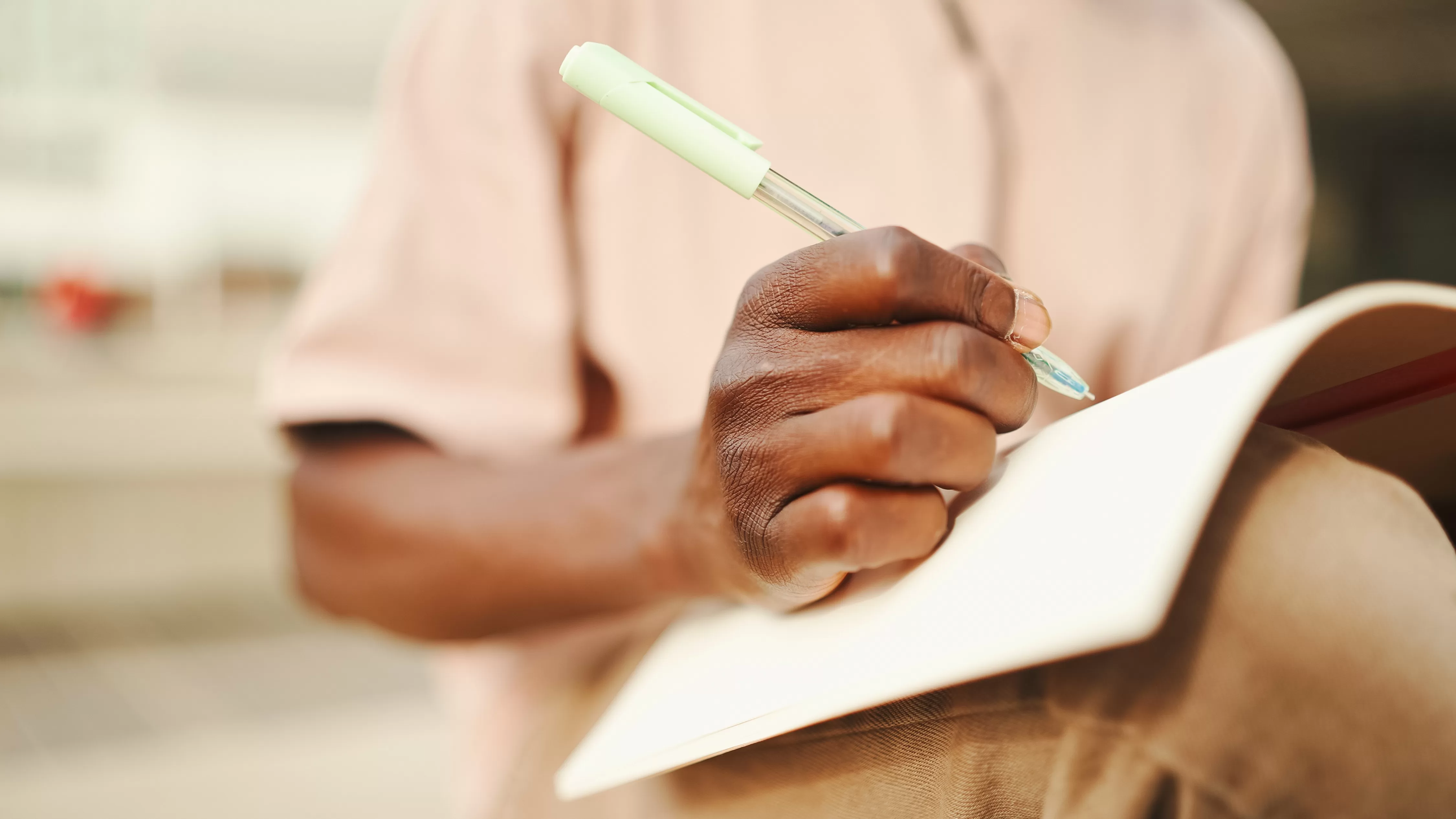 Close-up of young african student's hand taking notes. COSDEC National Vocational Certificate in Business Services