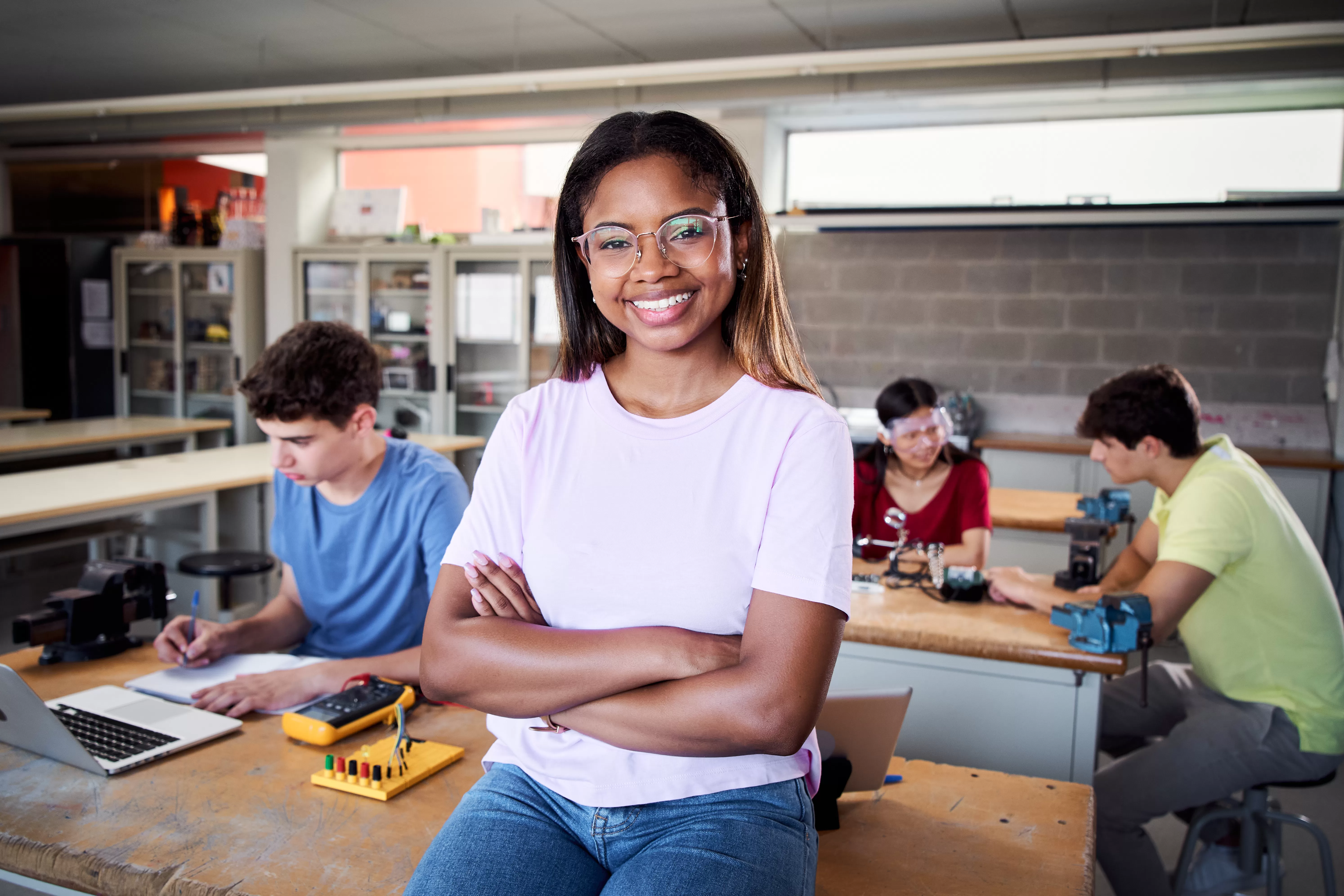 Seize the Moment With Marco Mpollo Vocational Training Centre: Portrait of a latina in the classroom looking at the camera with her arms crossed. Young students.